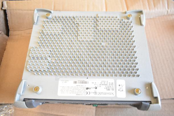 Sensormatic ZBSMPROE Antenna Deactivator, metal grid surface, fitted on cardboard. Labels show model, voltage, and compliance marks.