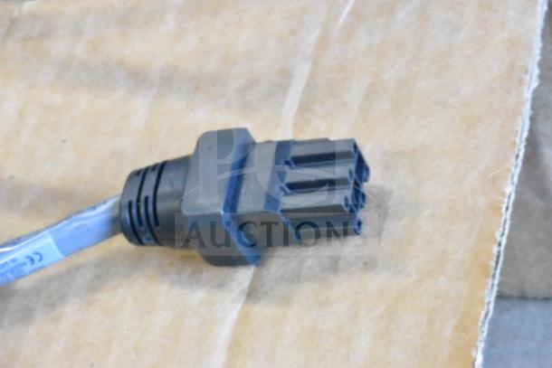 Black electronic connector on cardboard, part of a 12-item auction including Sensormatic deactivator and antenna.