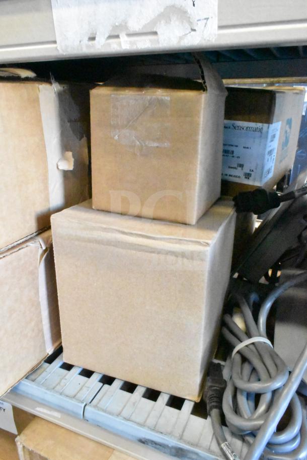 Cardboard boxes containing Sensormatic ZBAMB9012 and ZBSMPCPE antennas, Wren camera. Cables visible, ready for auction.