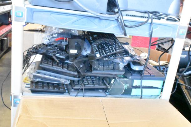 Lot of various computer peripherals including keyboards and mice, stacked on shelves, assorted brands and models.