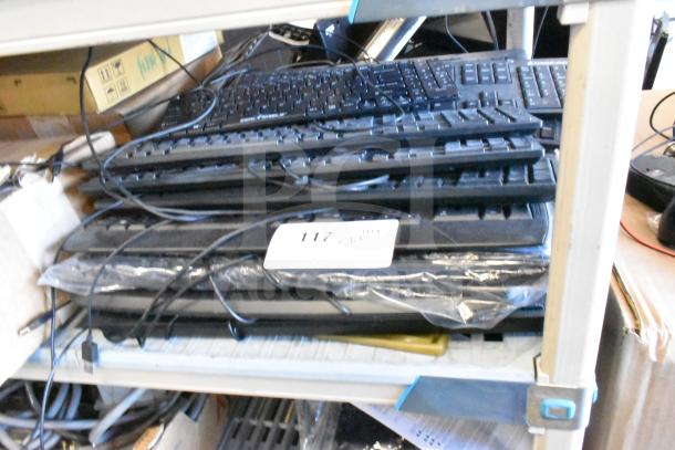 Lot of various items including multiple black computer keyboards stacked on metal shelves, with visible cables.