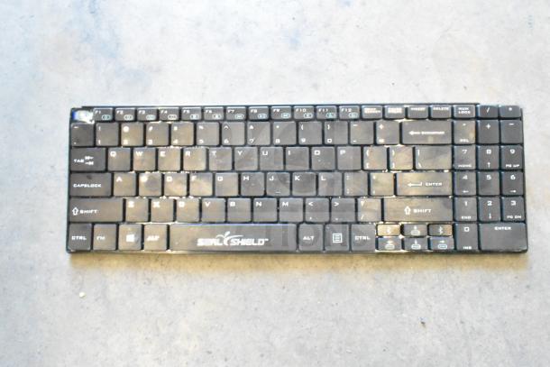 Seal Shield black computer keyboard, visible wear, keys slightly worn, functional condition, brand logo present.