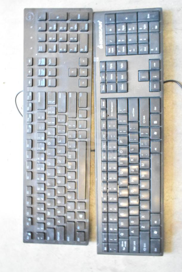 Lot of two black computer keyboards, labeled "keyboard" and "MICROSOUL," in used condition.