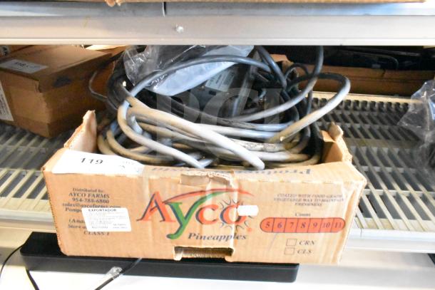 Seven assorted items including cables and a Sensormatic ZBSTPSP-L unit in a cardboard box, item tag visible.