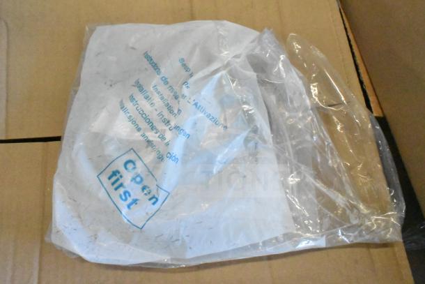 Clear bag with instructions and "Open first" label, containing miscellaneous items, including cables and a Sensormatic ZBSTPSP-L unit.