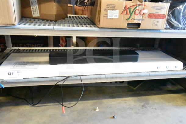 Bose sound bar on a shelf, black, in used condition, power cord visible, lot label QTY 121 displayed.