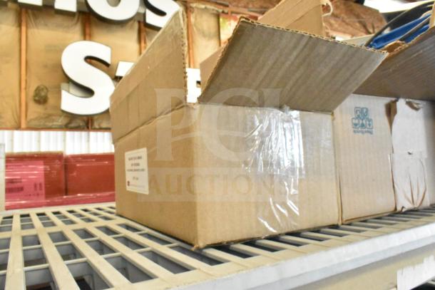 Open cardboard box containing a Sensormatic ZBAMB9012 label deactivator pad and computer keyboards, on metal shelving.