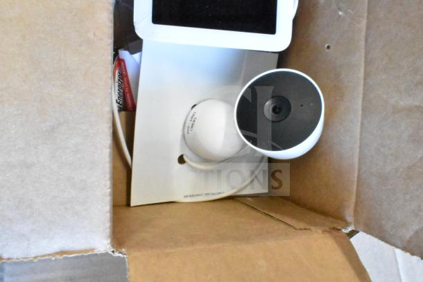 Box with various items including Sensormatic ZBAMB9012 label deactivator pad, some electronics, and a camera.