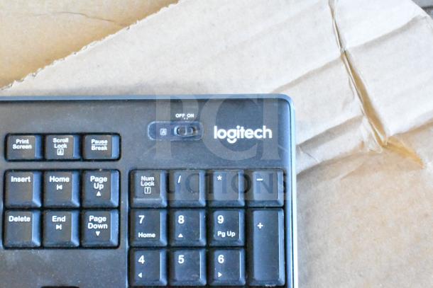 Logitech computer keyboard on cardboard, featuring numeric keypad and function keys, in good condition.
