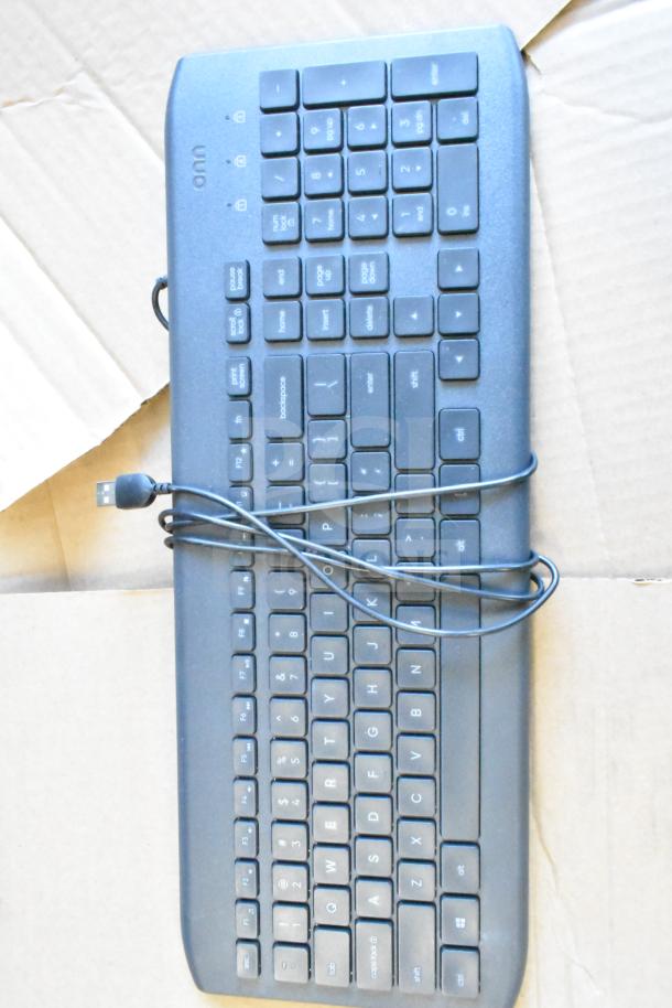 ONN computer keyboard with USB cable on cardboard. Part of a lot including a Sensormatic label deactivator.