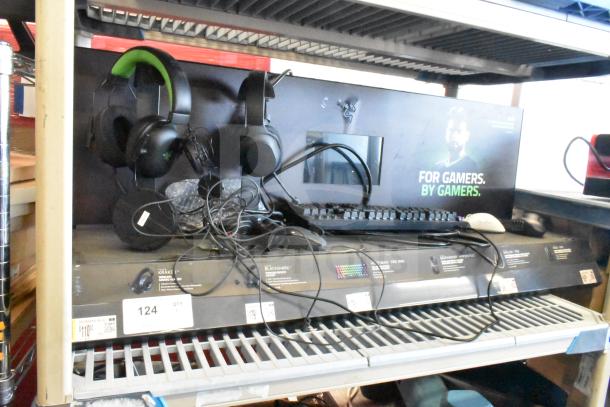 Gaming store display featuring headphones, keyboard, and computer mouse. Items on a shelf with price tags and promotional graphics.