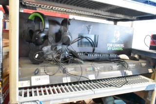 Gaming store display featuring headphones, keyboard, and computer mouse. Items on a shelf with price tags and promotional graphics.