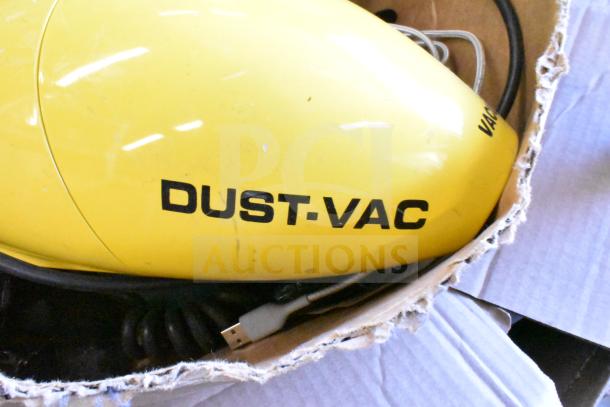 Yellow Dust Vac in used condition with visible cord, packaged in a cardboard box. Part of mixed items auction lot.