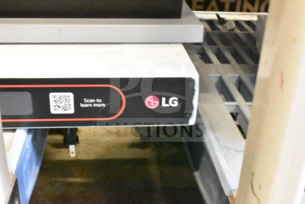 LG store display featuring a sound bar and speaker. Includes visible brand logo and QR code for more information. Slight wear.