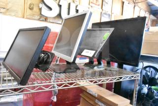 Four monitors on a shelf: Costar, HP Compaq LE1711, Elo TouchSystems, Acer S240HL. Includes visible model tag.