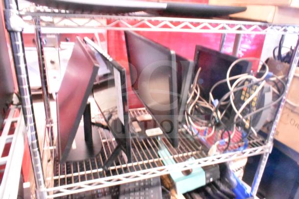 Five various monitors on a shelf, including HP, Onn ONA18HO015 21.5", Dell E2414Ht, and IBM, with cables visible.