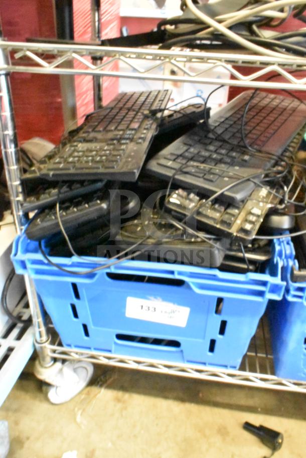 40 computer keyboards stacked in a blue crate, mixed condition, ready for auction. Item label: "133".