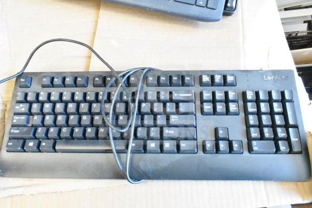 Lenovo wired keyboard on cardboard, part of 40 keyboard auction lot, showing QWERTY layout and numeric keypad.