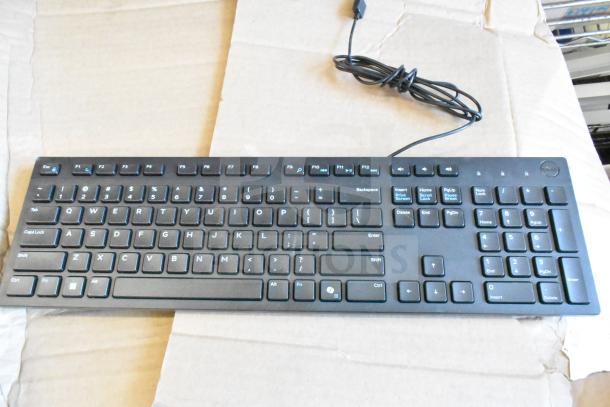 Black Dell wired keyboard on cardboard surface, standard layout, numeric keypad, good condition.