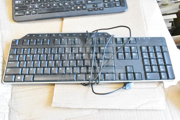A Dell wired USB keyboard on cardboard, part of a bulk lot of 40 used keyboards for auction.