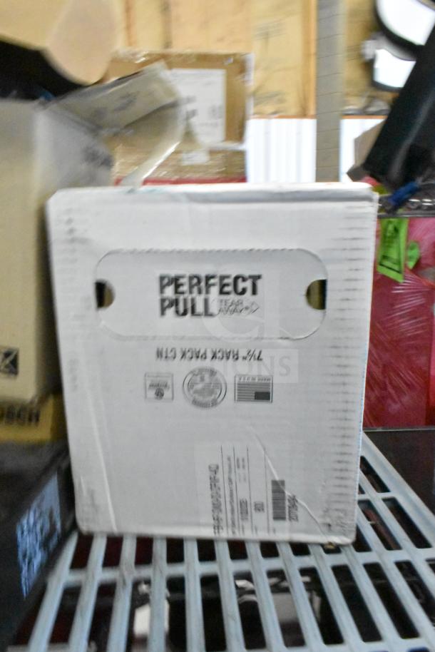 Box displaying "Perfect Pull Tear Away" label among assorted tech items, including surveillance camera gear and office equipment.