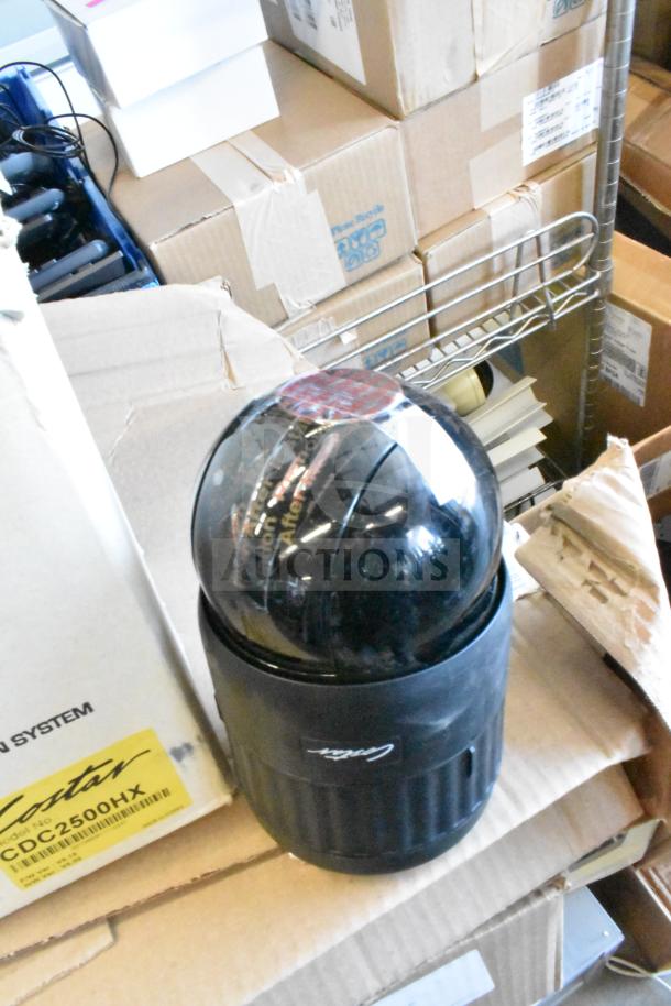 CCTV dome camera with Costar branding, black casing, surrounded by cardboard boxes, appears used.