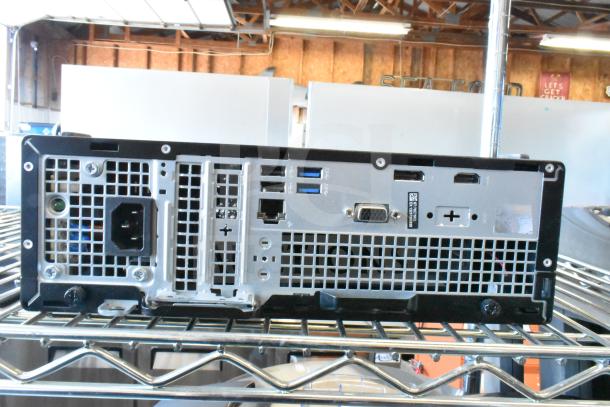 Back view of a Dell computer tower showing ports and ventilation, part of a lot with various tech items.