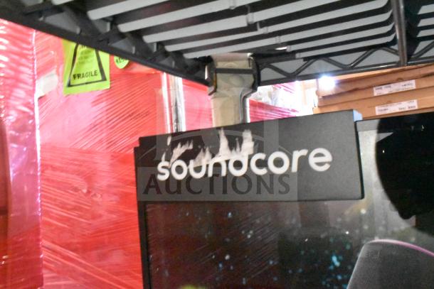 Soundcore store display with speakers, featuring a prominent logo. Display shows signs of wear with scuff marks.