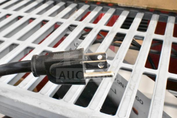 Power plug of LG store display with Xboom speaker, on a metal grid shelf.