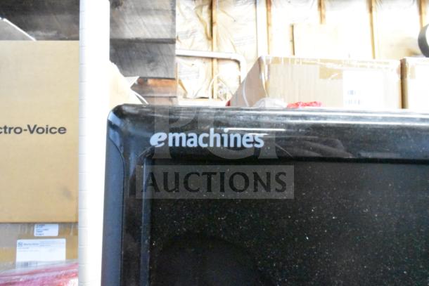 Emachines monitor with dust on screen in a storage area; included in auction of 25 assorted monitors (HP, Samsung, Dell).