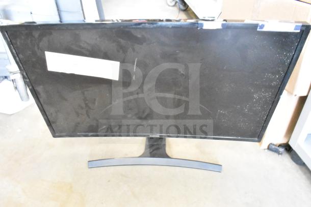 Samsung monitor with curved stand, part of 25-item auction. Slight wear visible. Placeholder tag attached.