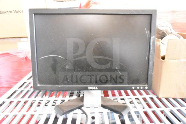 Dell monitor on a grid surface, visible scratches on screen, black frame, used condition.