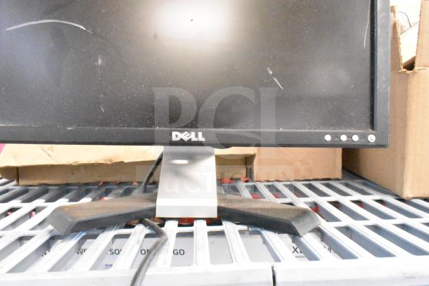 Dell monitor on a grate shelf, showing wear and scuffs. Part of the 25 various items auction, including HP and Samsung monitors.