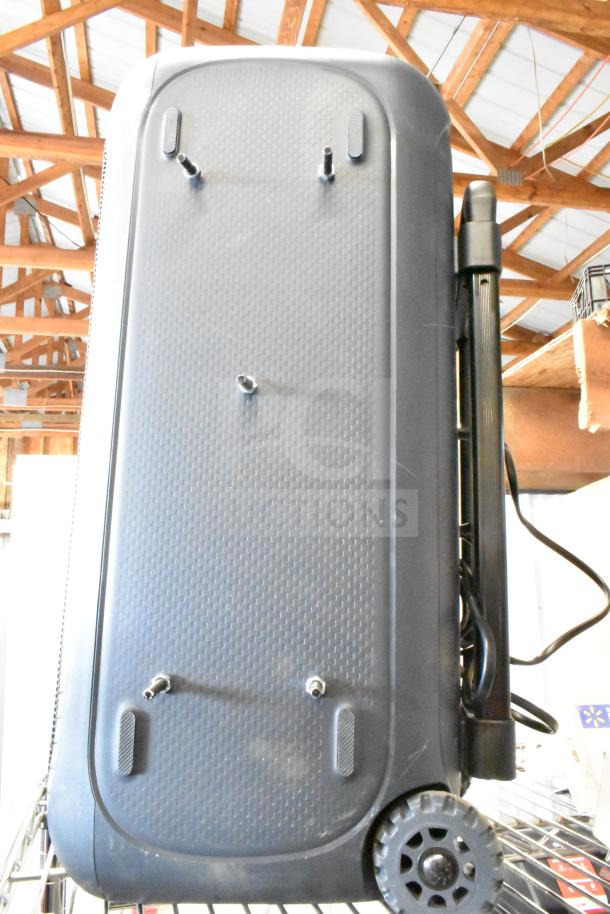 Portable speaker with wheels and handle, textured surface, visible mounting hardware, undersurface view, good condition.