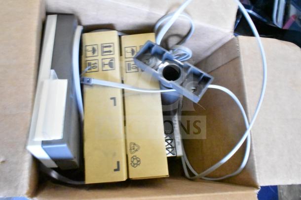 Lot of various items including a Toshiba Price Monitor in a cardboard box. Cables and packaged components visible.