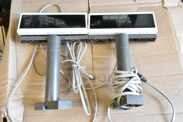 Lot of various items featuring two Toshiba price monitors with stand, cables coiled, and visible model markings, on cardboard.