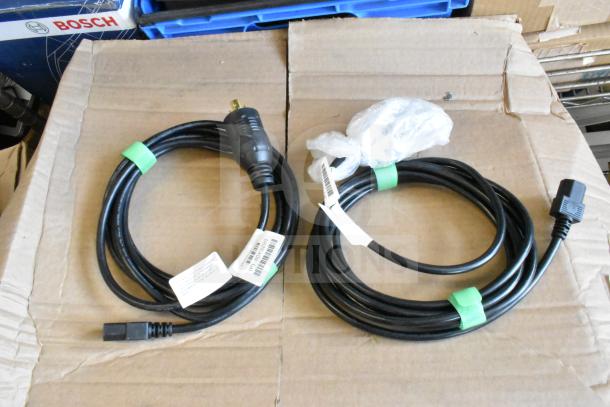 Assorted lot including power cables and Toshiba price monitor, tags visible, items in good condition on cardboard surface.