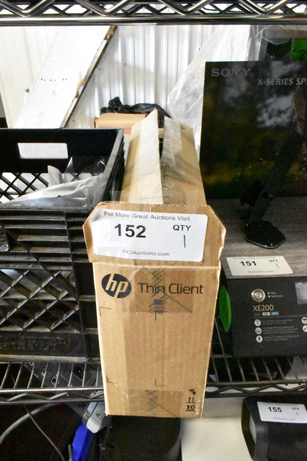 Cardboard box labeled "HP Thin Client" with auction tag 152, indicating quantity 1, by PCIAuctions.com.  