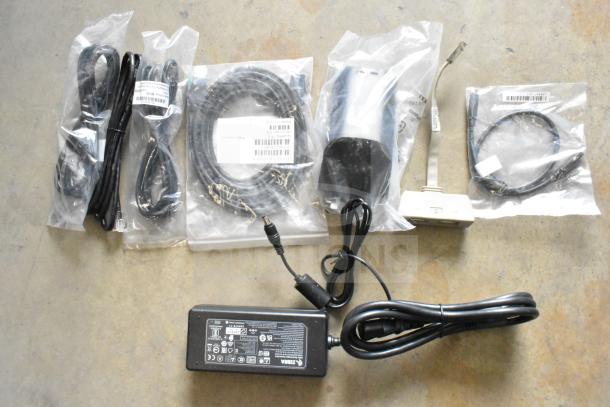 Lot of various cables and adapters in sealed packaging, includes power supply labeled Zebra. Suitable for electronic setups.