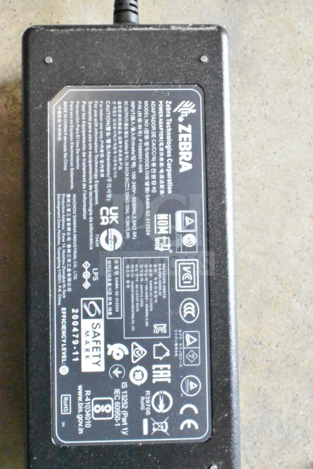 Zebra Technologies power adapter, specifications model SAW30-3125, with safety marks and certifications, black.