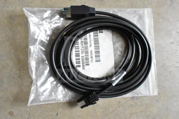 Lot of various items including a black cable, coiled. Visible label shows partial part number and barcode. In unopened packaging.