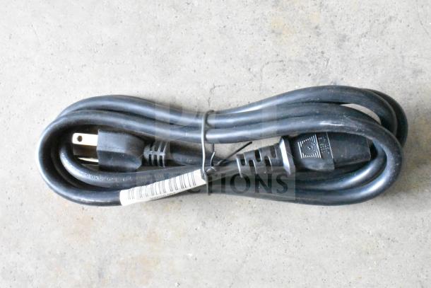 Coiled black power cable with plug and connector, labeled with barcode, part of a mixed item auction lot.