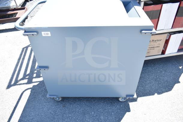 Gray metal unit with three compartments, commercial casters, handlebar, and barcode label.