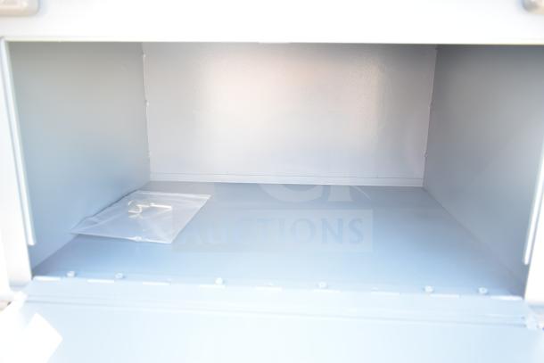 Gray metal unit with three compartments, featuring commercial casters. Interior view shown; appears in good condition.