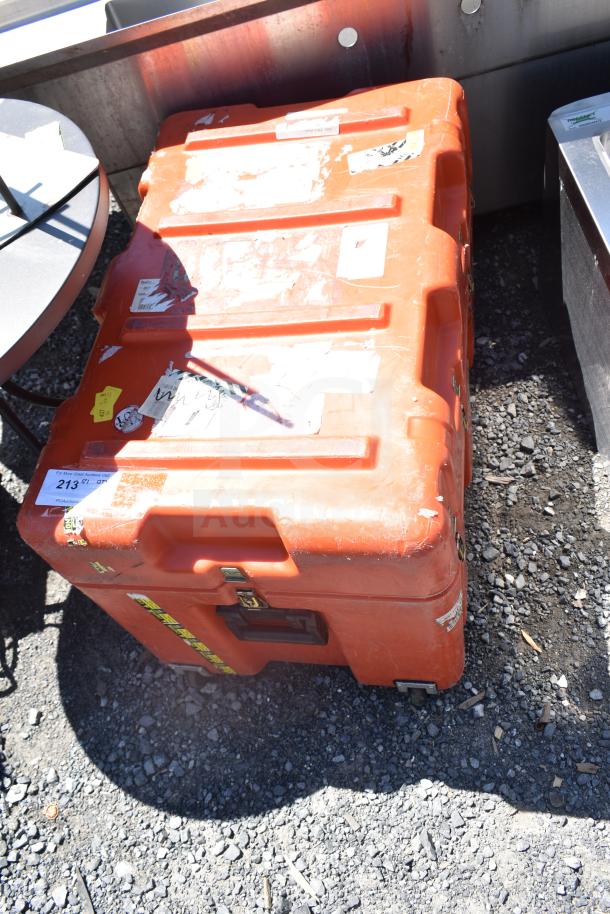 Orange industrial case with multiple stickers and latches, showing signs of wear. Suitable for equipment storage.