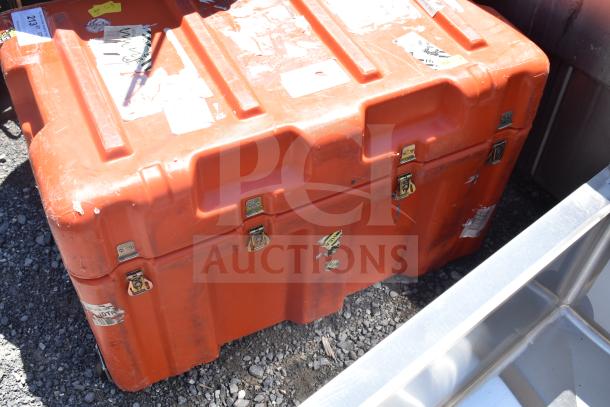 Orange case with sturdy latches, visible wear, and identification stickers on the surface.