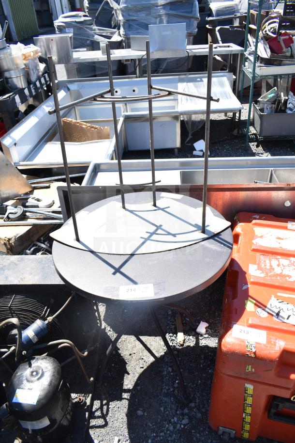 Two various metal tables, one upside down. Visible label shows "214". Outdoor setting, used condition.