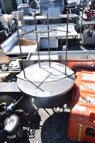 Two various metal tables, one upside down. Visible label shows "214". Outdoor setting, used condition.