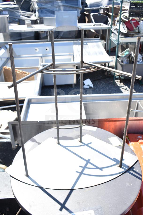 Two metal round tables with industrial design, showing visible wear. Background filled with various metal items.
