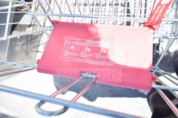Shopping cart on casters with red child safety seat. Visible warning label for child safety instructions.